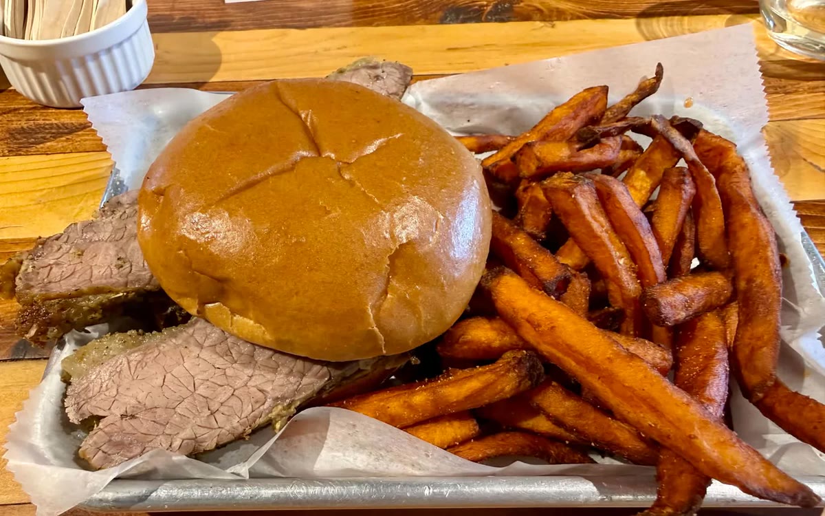 A house-smoked brisket sandwich with hand-cut sweet potato fries.